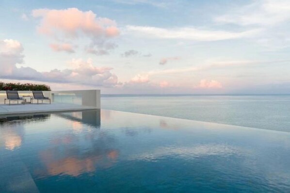 An infinity pool with a clear view of the ocean and a modern structure with seating. - Huzhiyun Hotel (Chengjiang)