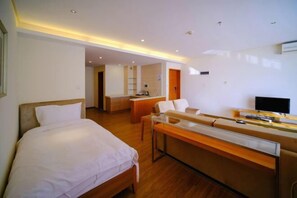 A modern hotel room with a bed, a desk, a chair, a television, and a bathroom visible in the background. - Huzhiyun Hotel (Chengjiang)