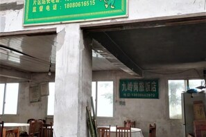 A room with exposed concrete pillars, a green sign with contact information, and a window with a view.