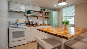 A modern kitchen with white cabinets, a wooden countertop, and a green refrigerator. - New Cottage: 4th row & fully fenced back yard! (Hilton Head Island)