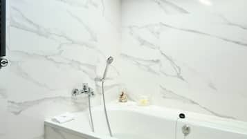 A modern bathroom with a skylight, a bathtub, and marble walls.