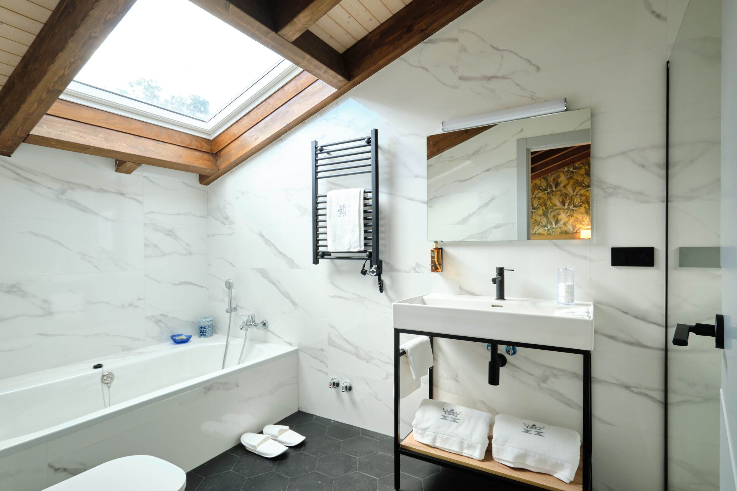 Un baño moderno con tragaluz, una bañera independiente, un tocador con espejo y un perchero para toallas.