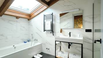Un baño moderno con tragaluz, una bañera independiente, un tocador con espejo y un perchero para toallas.