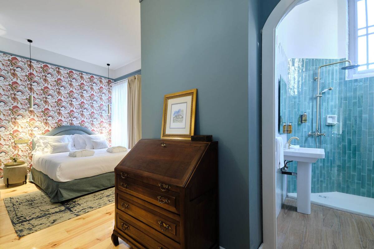 Une chambre à coucher comprenant un lit, une commode et une salle de bain avec douche et lavabo.