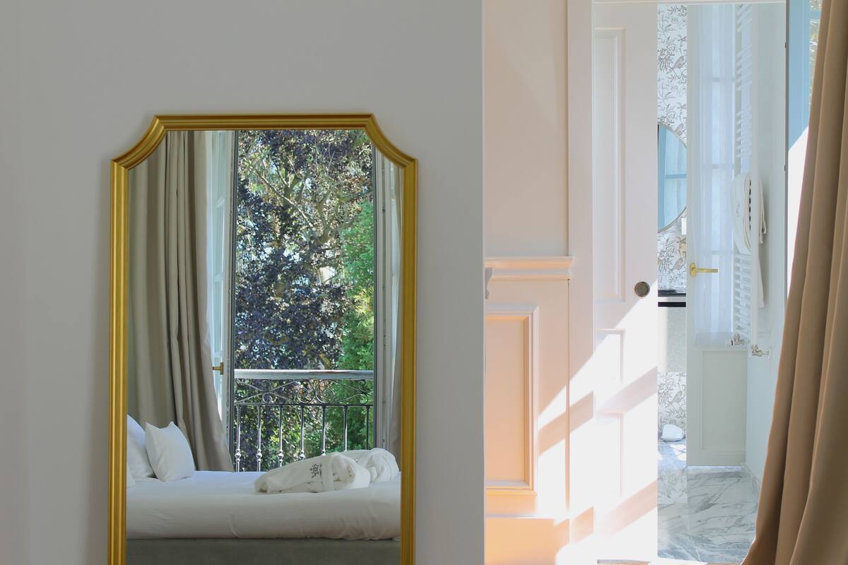 Une chambre avec une grande fenêtre, un lit et une vue sur la verdure.