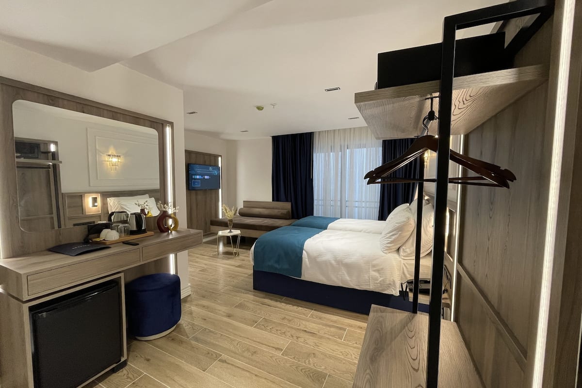 Hotelkamer met een bed, nachtkastje, spiegel, televisie en een kledingkast met hangroede.