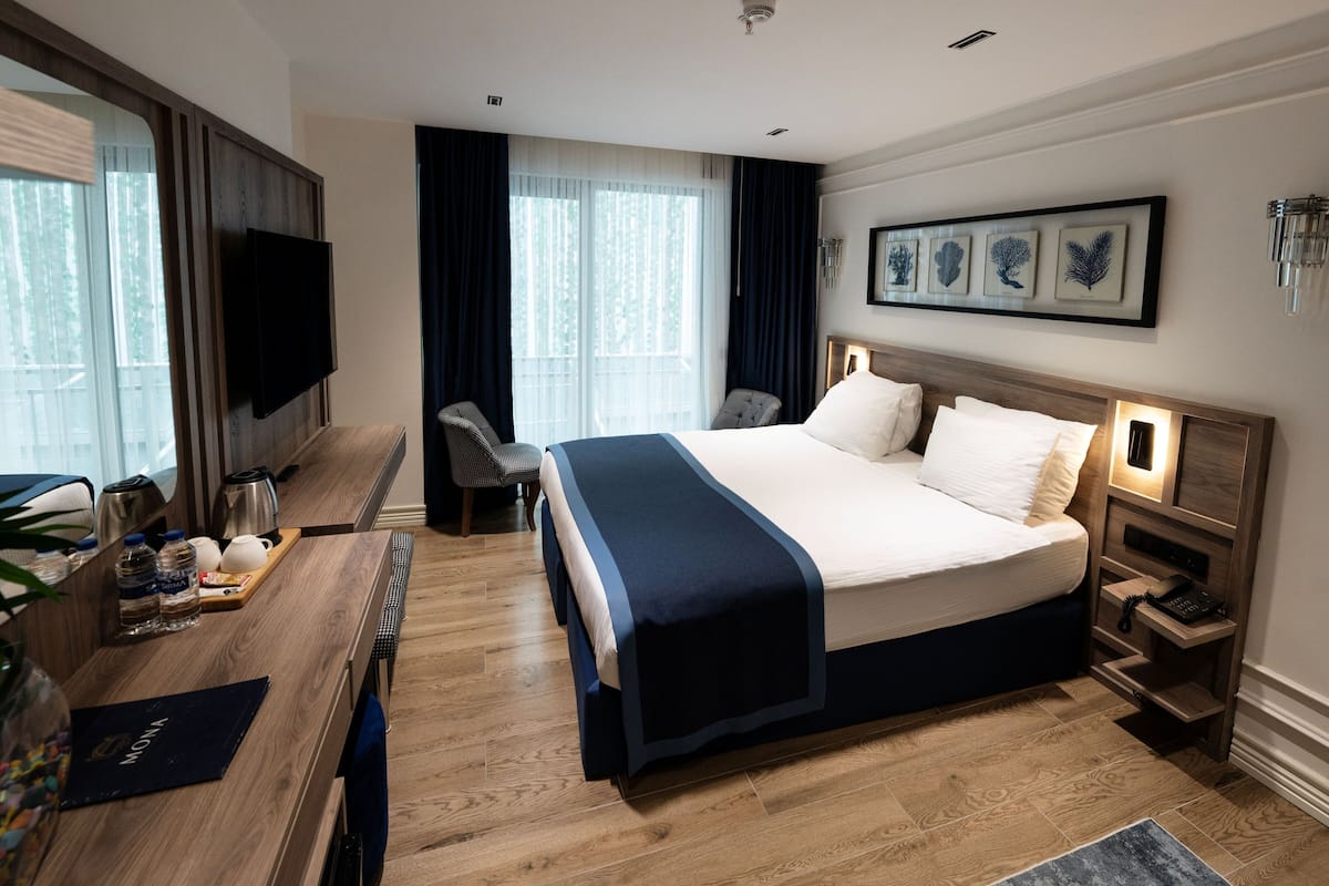 Hotelkamer met een groot bed, nachtkastjes, een bureau met stoel, een televisie en kunst aan de muur.