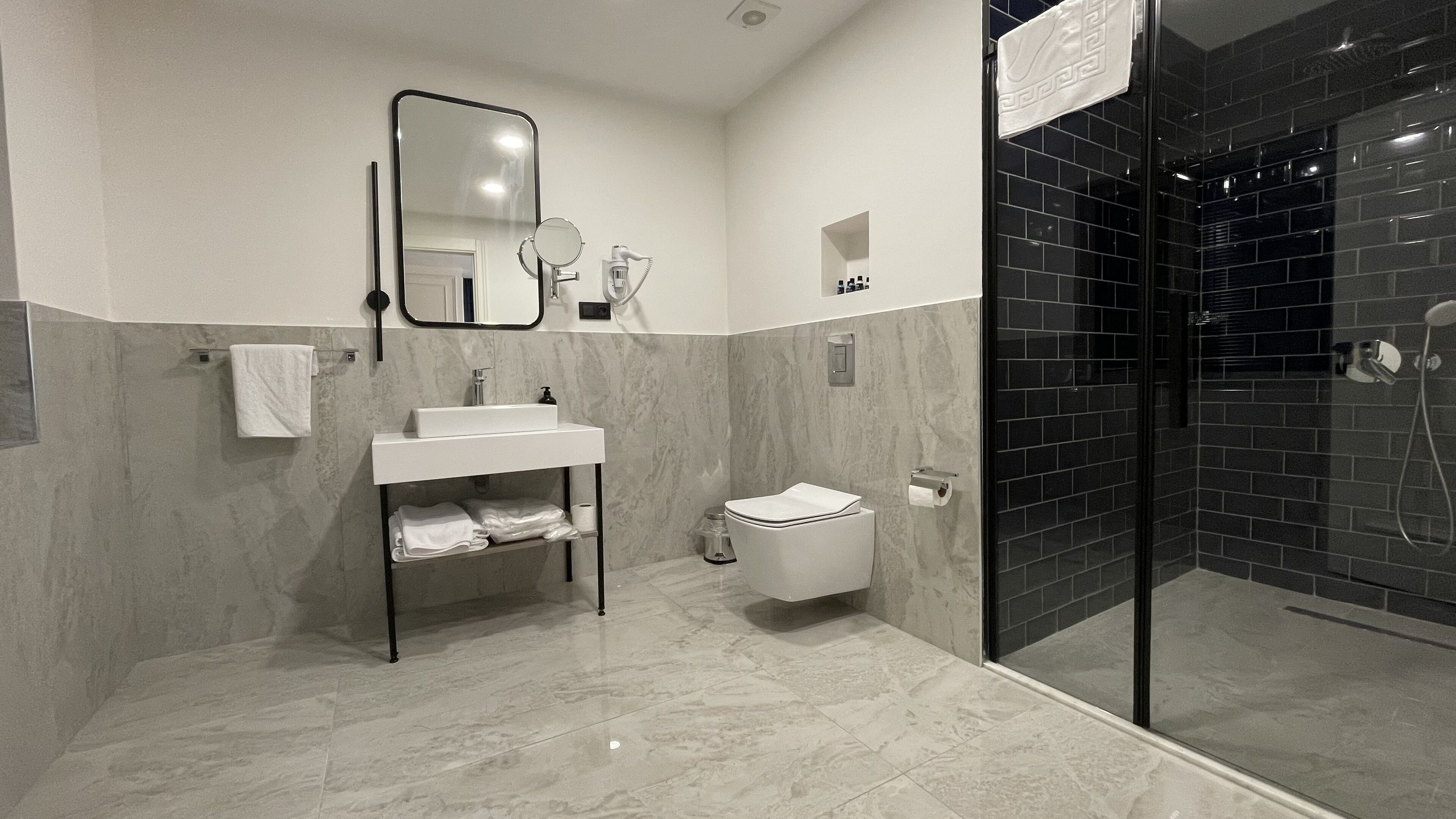 Une salle de bain moderne avec un lavabo blanc, un miroir et des toilettes.