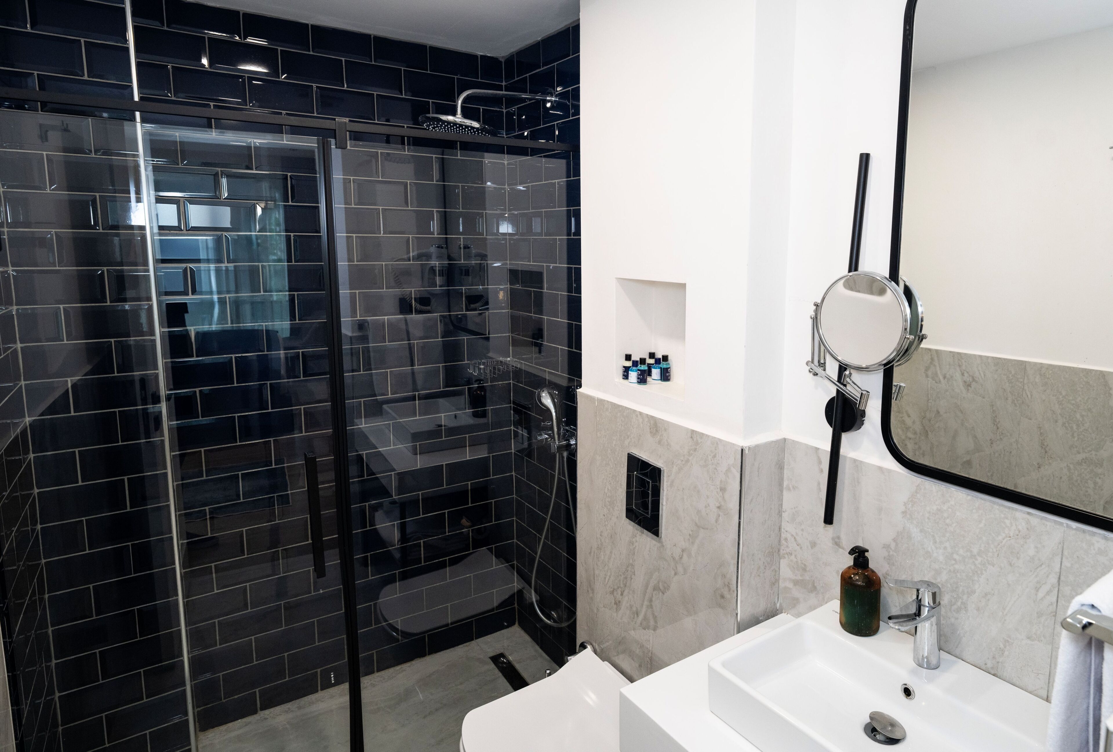 A modern bathroom with a glass-enclosed shower, a white sink, and a mirror.