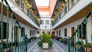 Une cour intérieure avec un jardin central, des plantes en pot et des bancs.