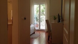 Un estrecho pasillo que conduce a una habitación con una cama, una silla y una pequeña mesa.