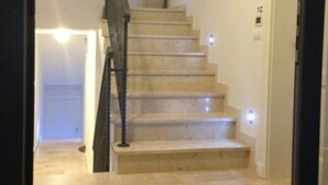 Una escalera con barandilla y un florero en el rellano.