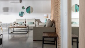 A modern living room with a sofa, coffee table, and a brick accent wall. - Hommyhome Triana Boutique Apartments 004 (Sevilla)
