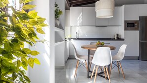 Eine moderne Küche mit weißen Schränken, einem runden Holztisch und zwei weißen Stühlen.