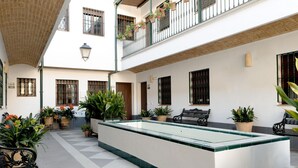 Ein Innenhof mit einem zentralen Pool, Kübelpflanzen und Sitzmöglichkeiten im Freien.