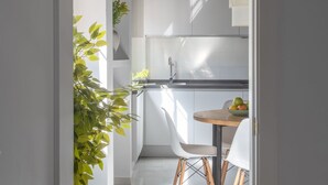Una cocina moderna con armarios blancos, un lavamanos de acero inoxidable y una mesa redonda de madera con sillas.