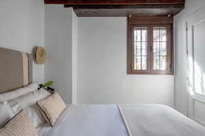Une chambre à coucher avec un lit, une fenêtre et une poutre en bois au plafond.