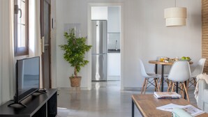 A modern living room with a flat-screen TV, a wooden coffee table, and a dining area with a table and chairs.