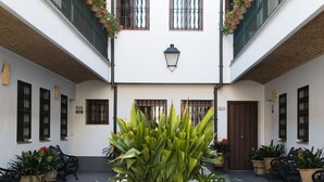 A courtyard with potted plants, a tiled floor, and a central decorative element.