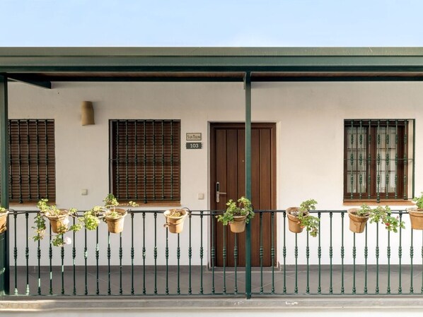 A building with a white facade, a wooden door, and a balcony with potted plants. - Hommyhome Triana Boutique Apartments 106 (Sevilla)
