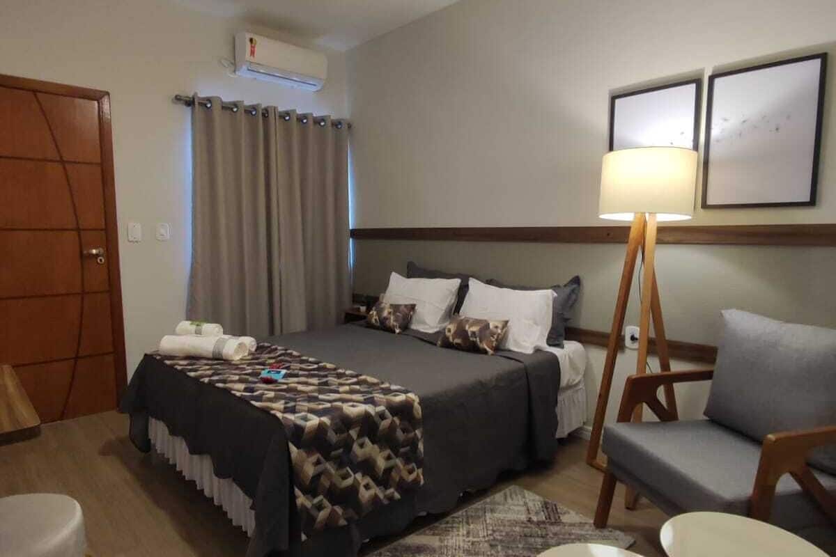 A hotel room with a bed, a desk, a chair, a lamp, and a ceiling fan.