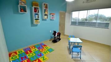 A classroom with alphabet foam mats, a horse-shaped toy, and shelves with toys and books.