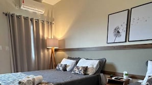 A hotel room with two beds, a ceiling fan, an air conditioning unit, a lamp, and two framed pictures on the wall. - Hotel Capital da Fé (Aparecida)
