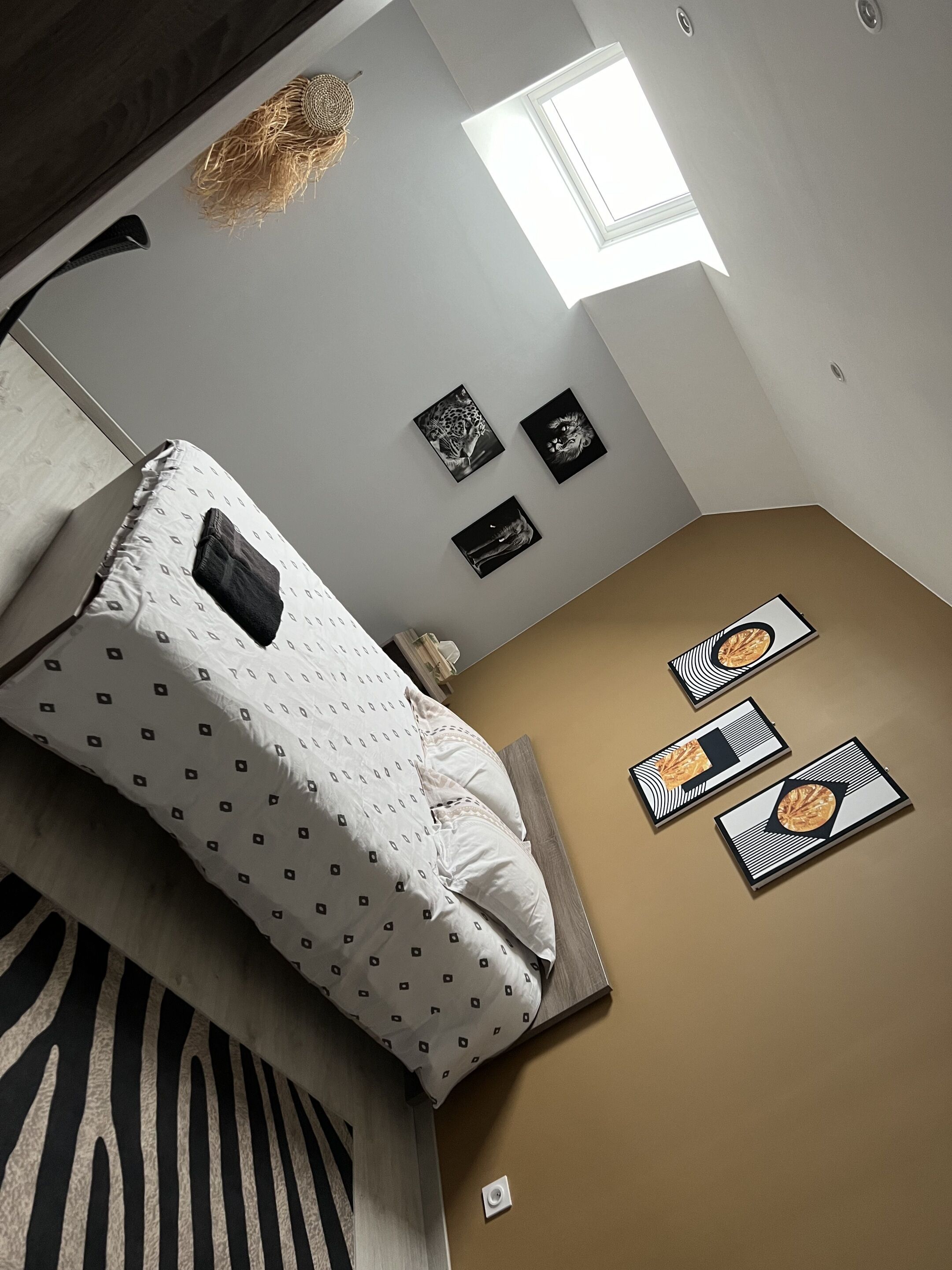 Een slaapkamer met een bed, een tapijt met luipaardprint, een dakraam en wanddecoratie.
