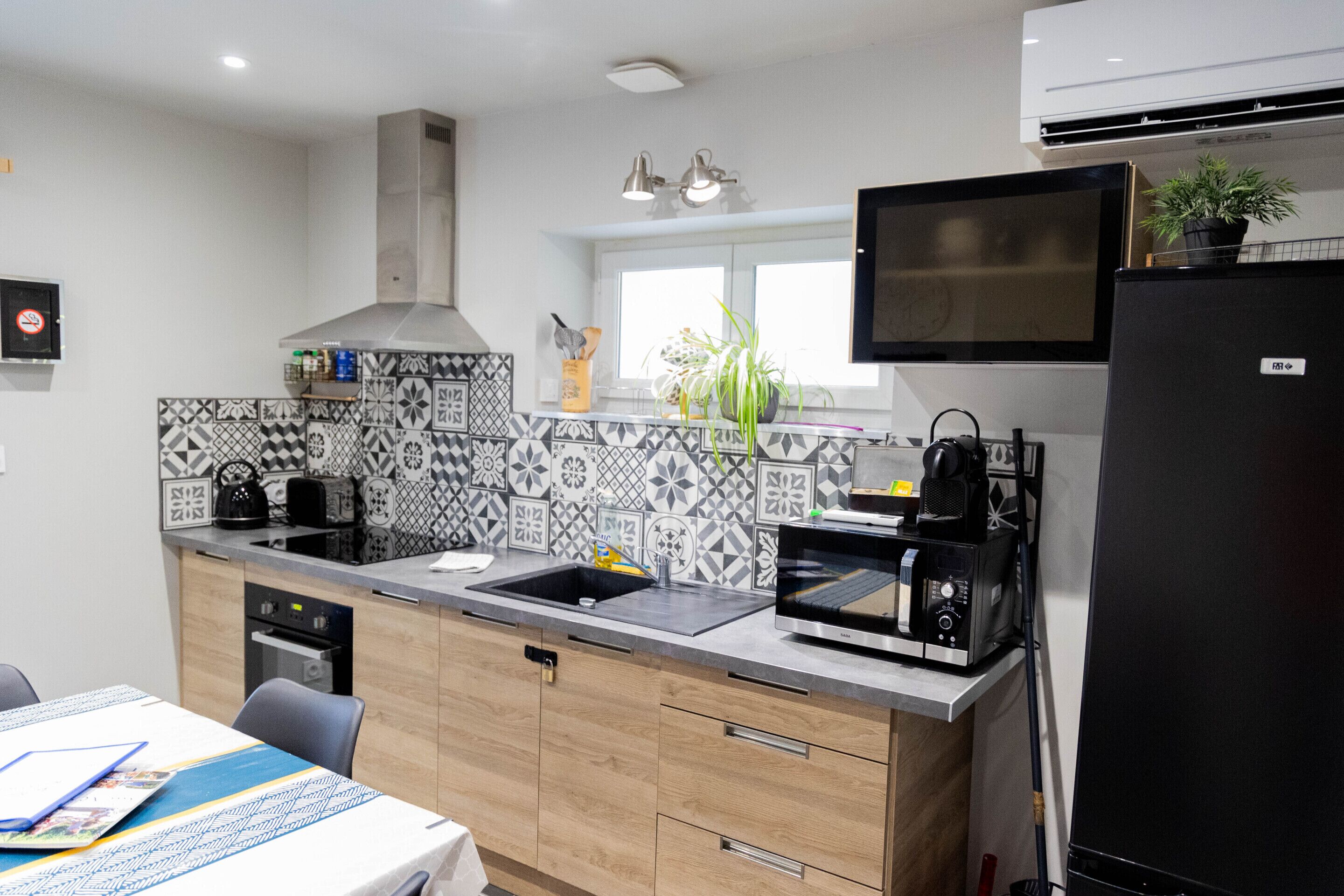 A modern kitchen with a microwave, toaster, sink, and a black refrigerator.