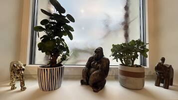 A window sill with three potted plants and two animal figurines.