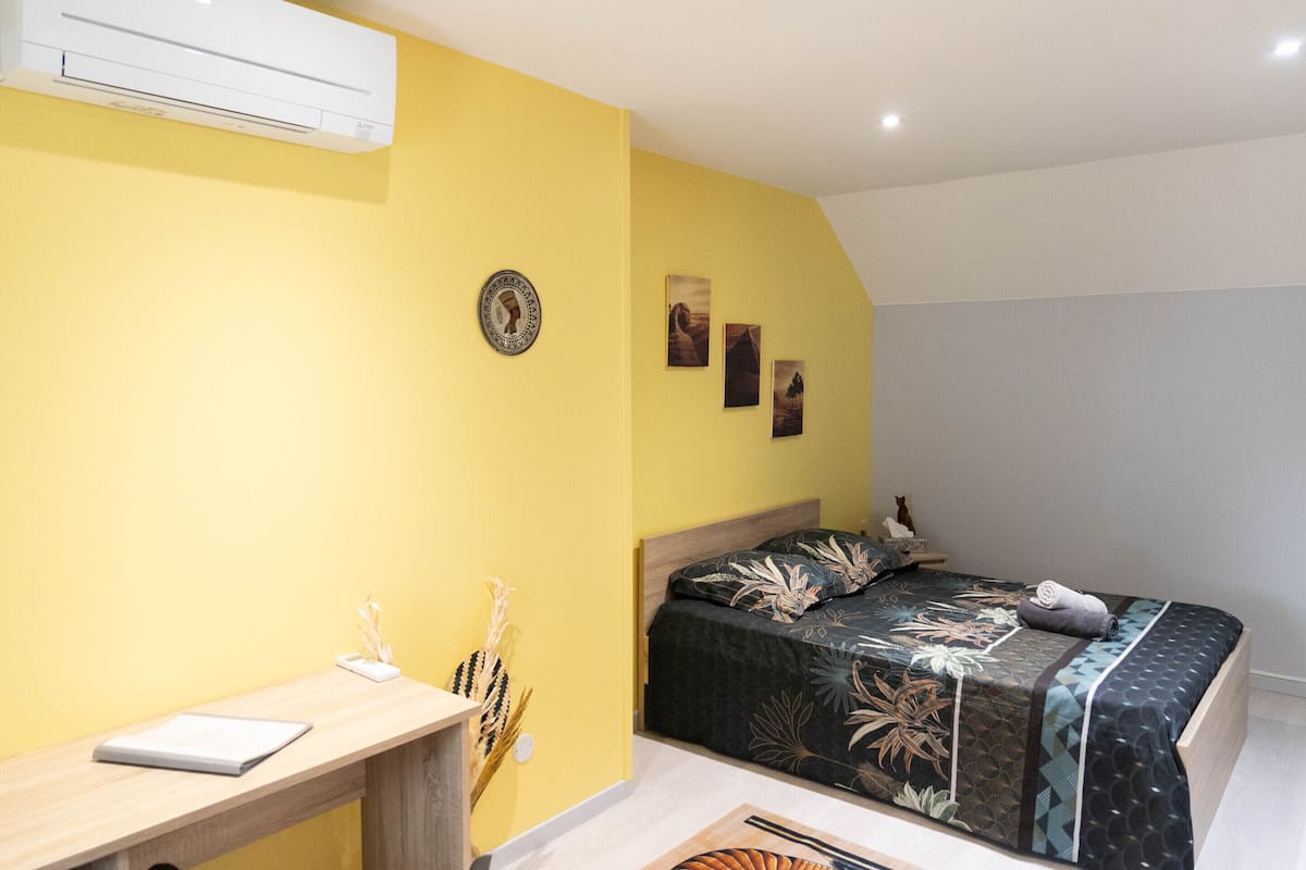 Ein Schlafzimmer mit einem Bett, einem Schreibtisch und einer Wand-Klimaanlage.