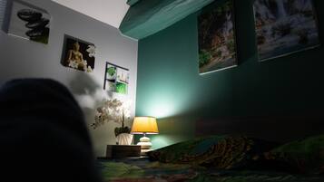 Un dormitorio con cama, mesita de noche, lámpara y decoración en la pared, incluyendo una estatua de Buda y una pintura de cascada.