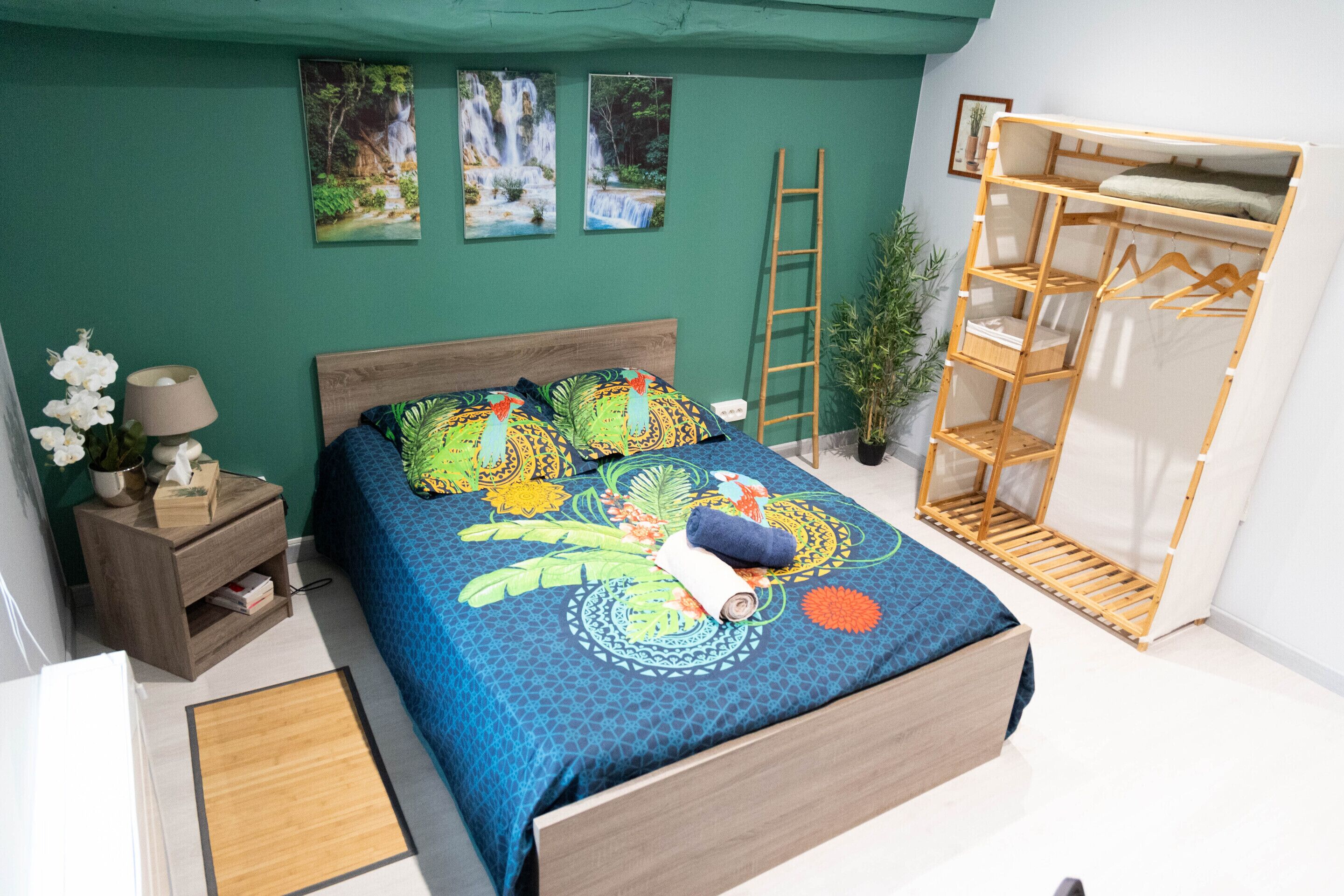 Een slaapkamer met een bed, nachtkastje, houten trap, plant en een houten plankunit.