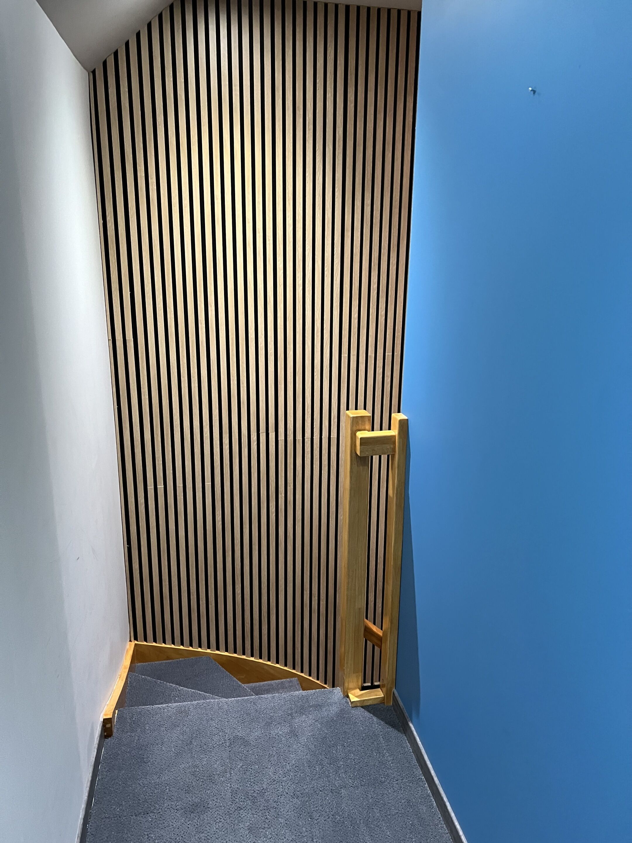 Una esquina de una habitación con techo inclinado, panel de pared de madera y pared azul.