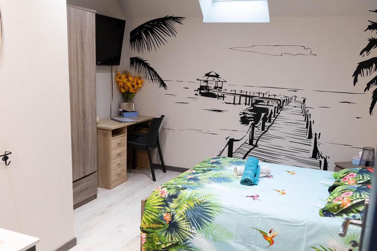 Ein Schlafzimmer mit Bett, Schreibtisch und einer Wandmalerei vom Strand.