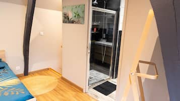 Una habitación pequeña y funcional con cama, zona de ducha y acceso a un baño.