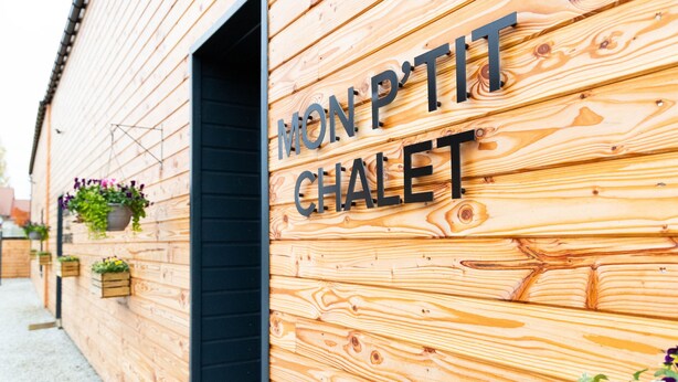 Un mur extérieur en bois portant l’inscription « MON P’TIT CHALET », indiquant qu’il s’agit d’un petit hébergement de style chalet.