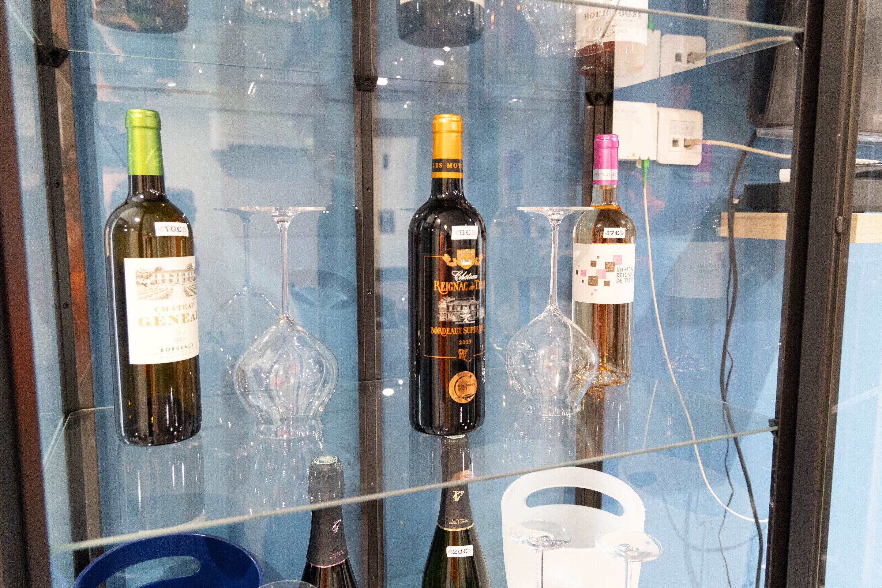 Eine Auswahl an Weinflaschen und Gläsern in einer Glasvitrine.