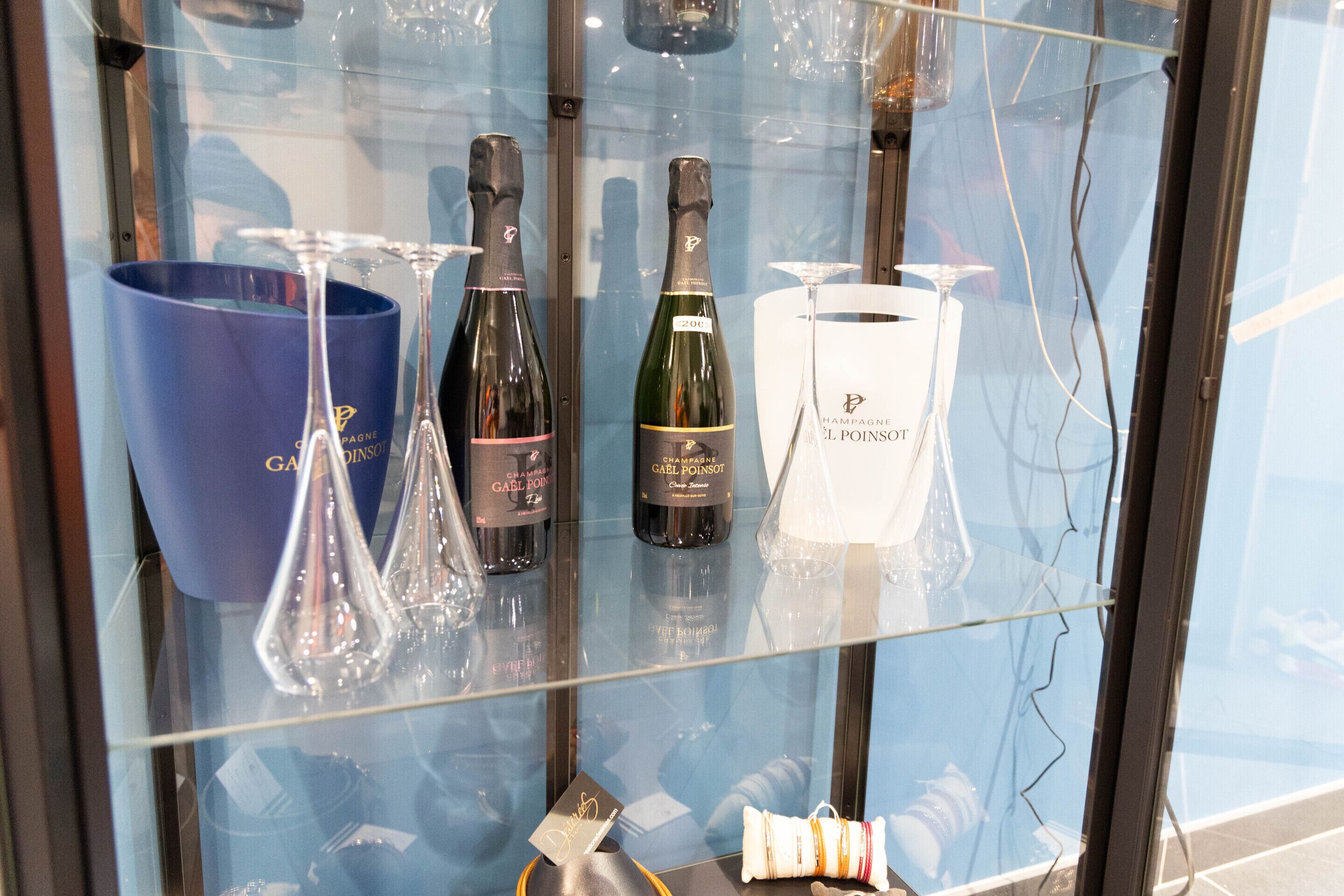 A display case containing various bottles of champagne and a blue bucket.