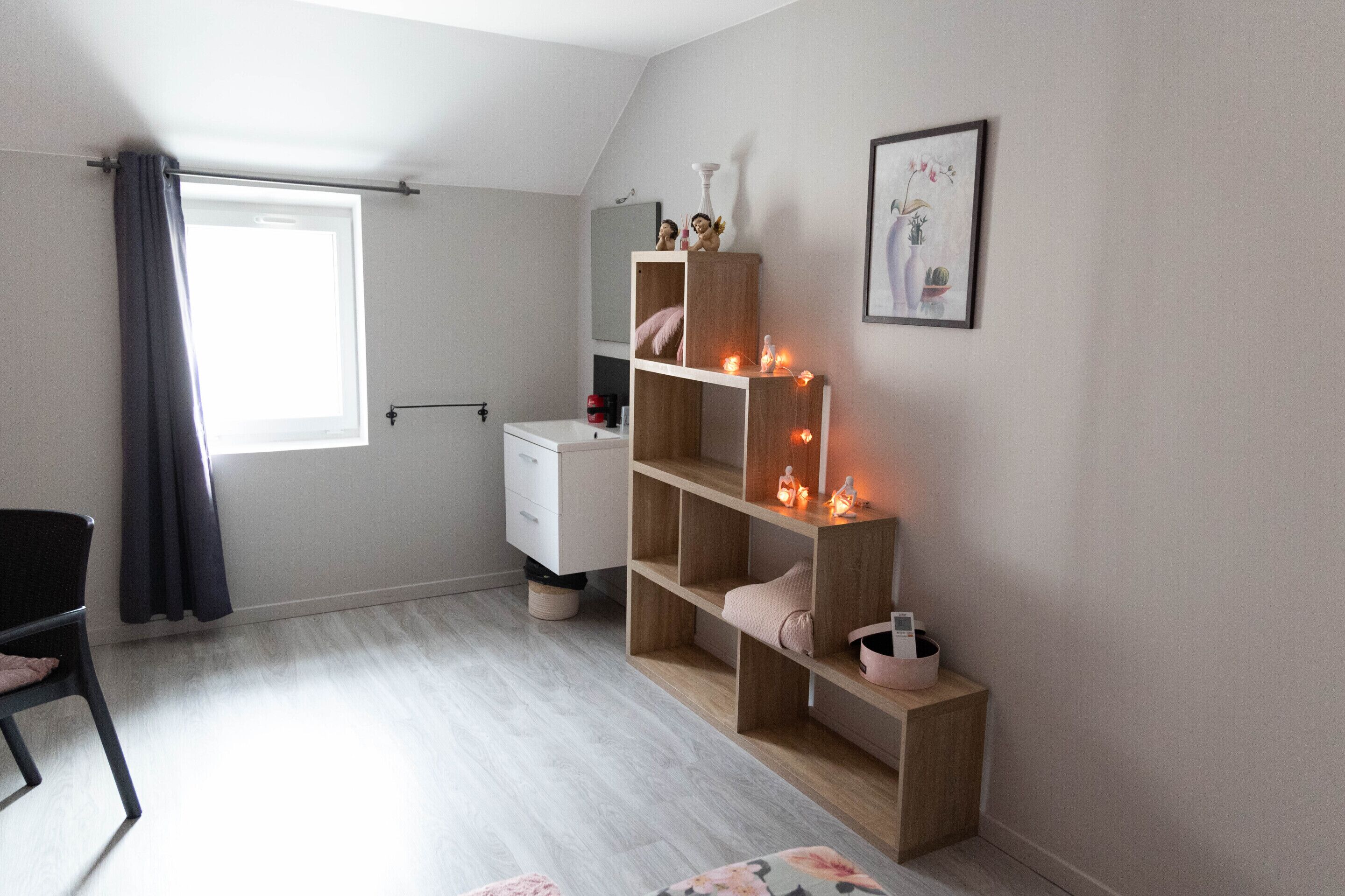 Une chambre avec une fenêtre, un bureau, une armoire et une table de chevet.