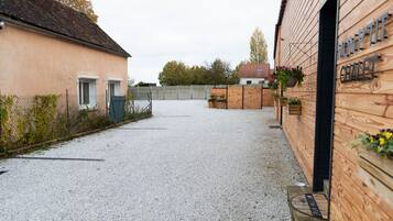 Ein Schotterweg führt zu einem Gebäude mit Holzfassade und einem Schild mit der Aufschrift 'MON P'TIT CHALET'.