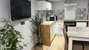 Une cuisine moderne équipée d’un téléviseur à écran plat, d’un four à micro-ondes et d’un coin repas avec une table et des chaises.
