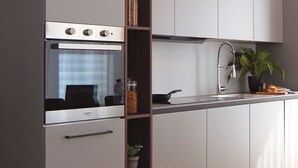 A modern kitchen with grey cabinets, a built-in oven, and a sink. - AR Noho Apartment (Bergamo)