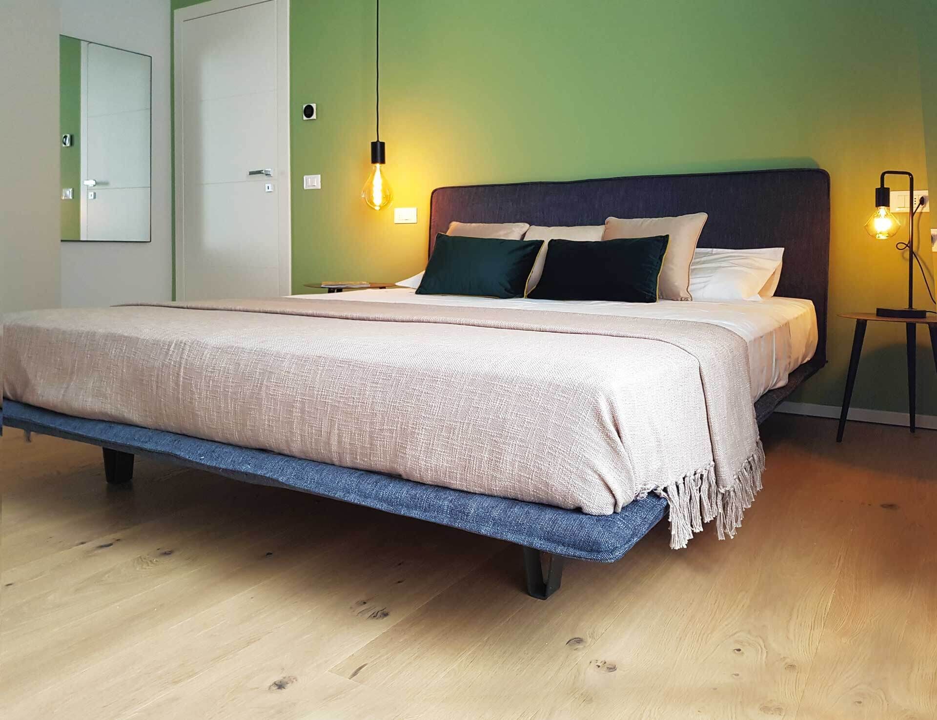 Un dormitorio moderno con cama, lámparas de noche y suelo de madera.