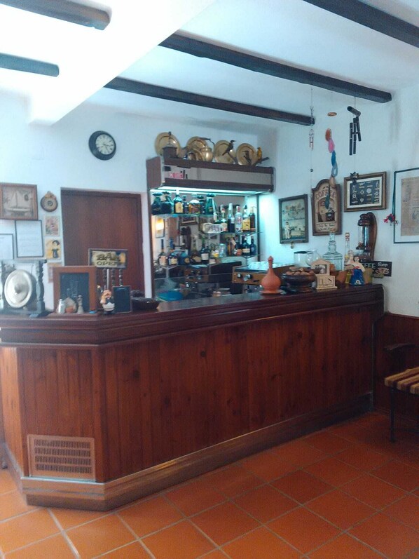 A bar area with wooden counter, shelves with bottles, and various decorations. - Hotel das Termas (Idanha-a-Nova)