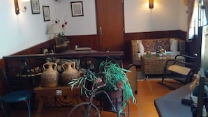 Un salon chaleureux avec un canapé, une table basse, un vélo décoré de plantes et un téléviseur fixé au mur.