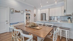 A modern kitchen with white cabinetry, a central island, and pendant lighting. - Seas The Day @ West Side Cottages | Community Pool (Gulf Shores)