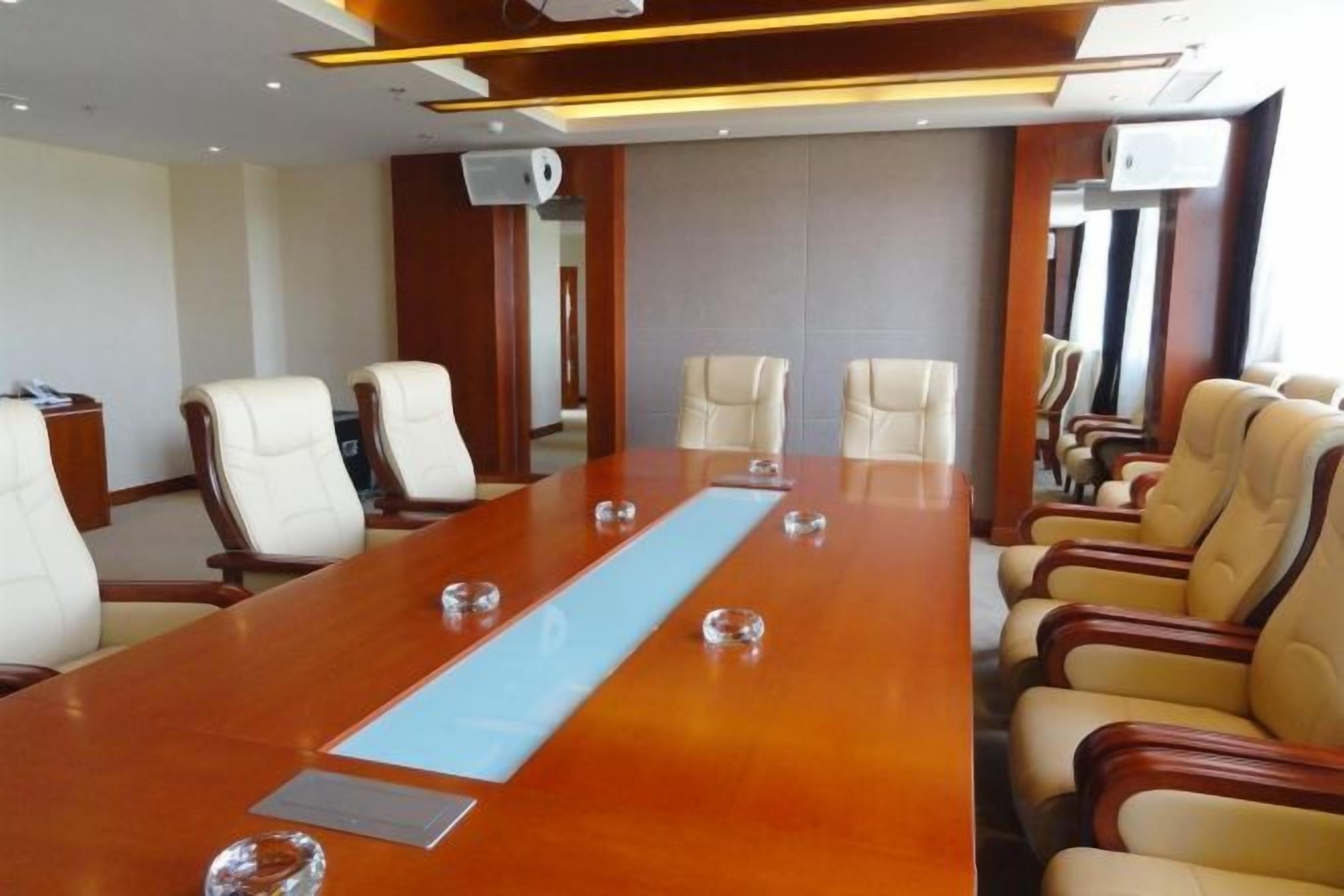 A conference room with a long table, multiple chairs, and a projector screen.