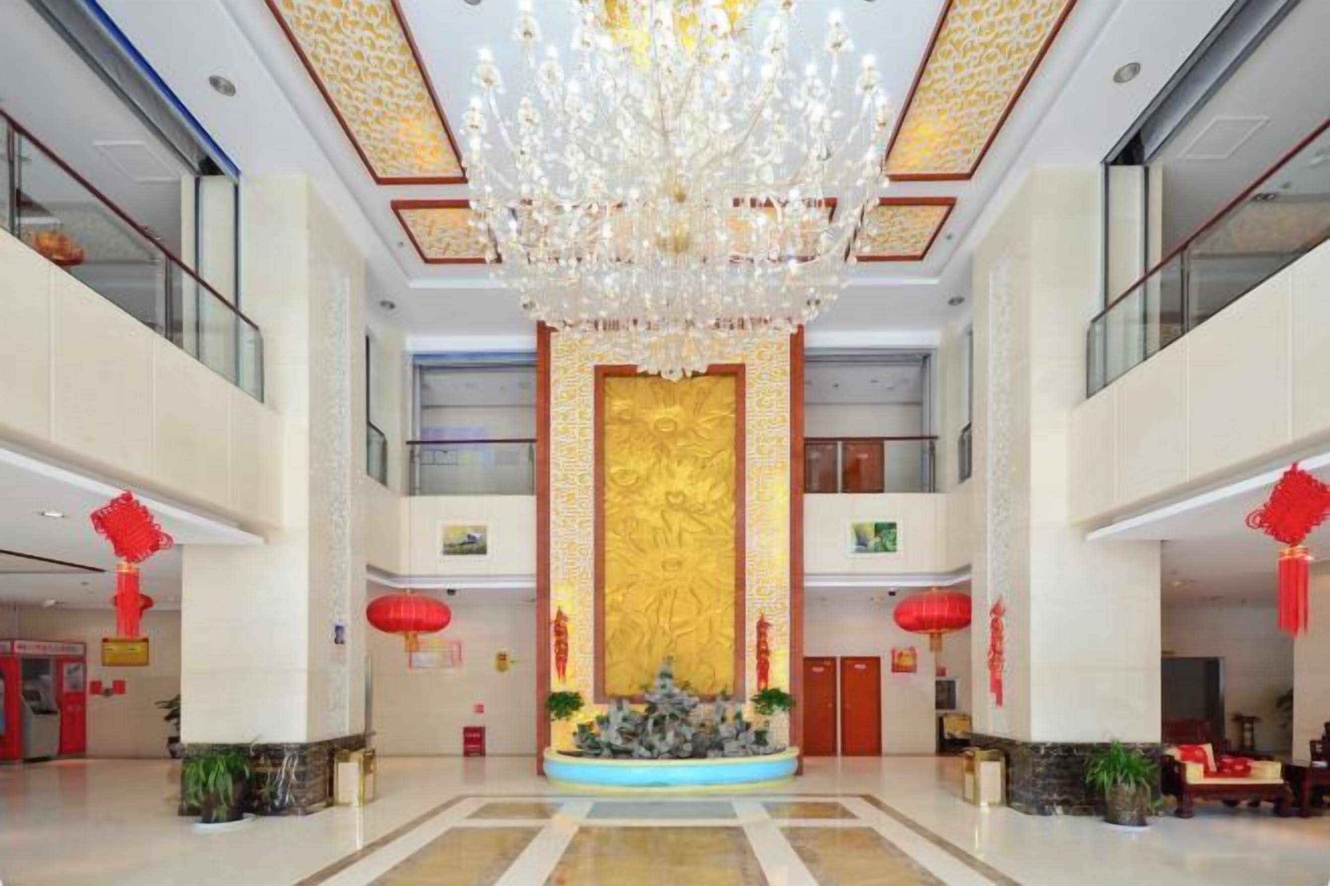 A spacious lobby with a grand chandelier, a central decorative wall, and red lanterns.