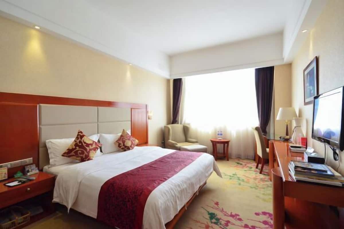 Una habitación de hotel con una cama grande, un escritorio, una silla y un televisor.